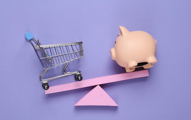 Photo balancing swing with piggy bank and shopping trolley on purple pastel background minimalism geometry shapes creative layout