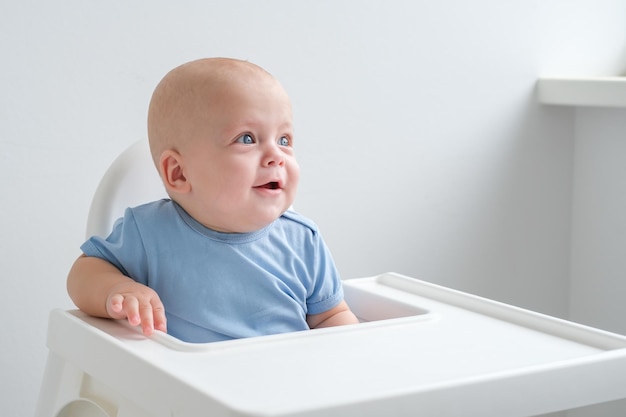 bald baby boy 3 months sitting in baby chair on white background