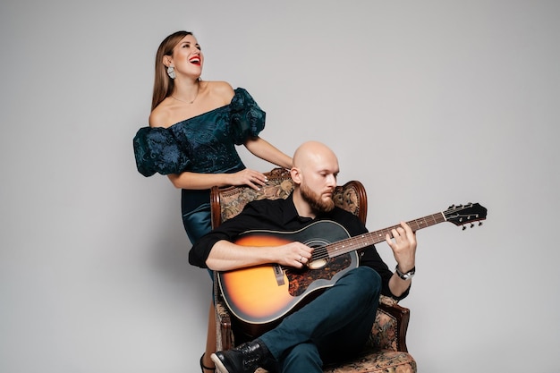 Bald bearded guy plays the guitar The woman sings a song Acoustic duet