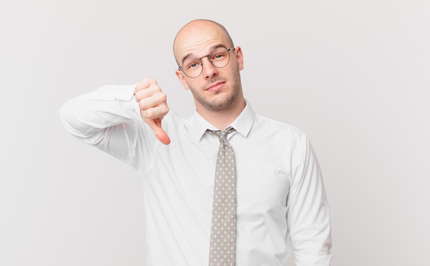 Bald businessman feeling cross, angry, annoyed, disappointed or displeased, showing thumbs down with a serious look