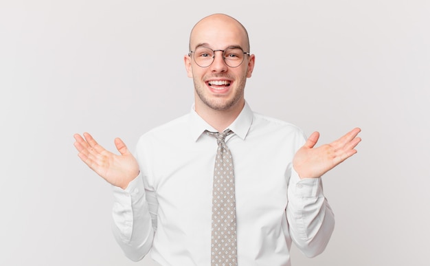 Bald businessman feeling happy, excited, surprised or shocked, smiling and astonished at something unbelievable