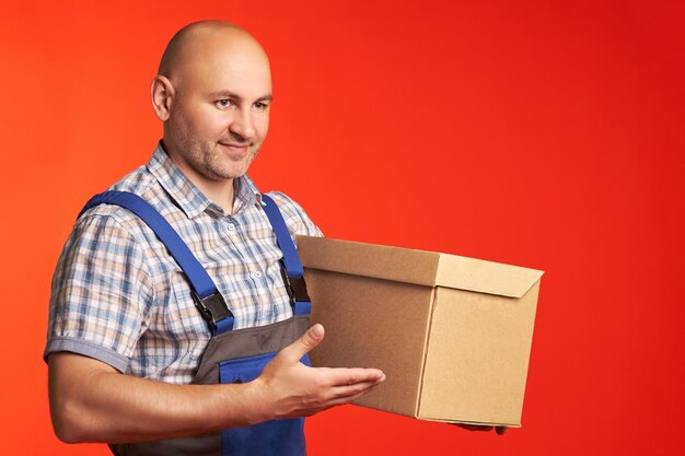 Bald male loader dressed in special clothes delivered a parcel
in a box