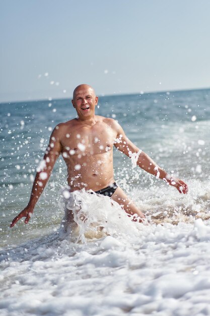 Bald man on the beach by the sea on vacation