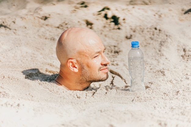 Bald man buried in sand