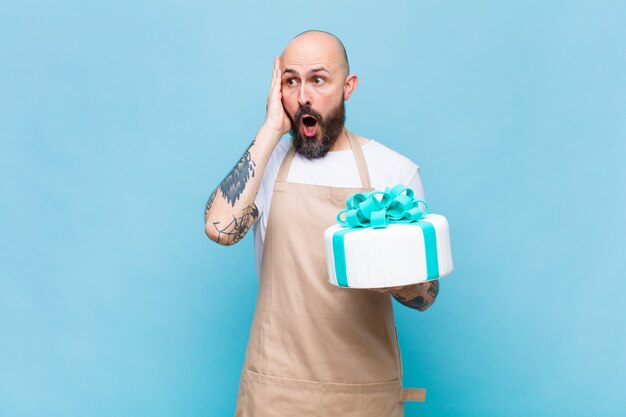 Bald man feeling happy, excited and surprised, looking to the side with both hands on face