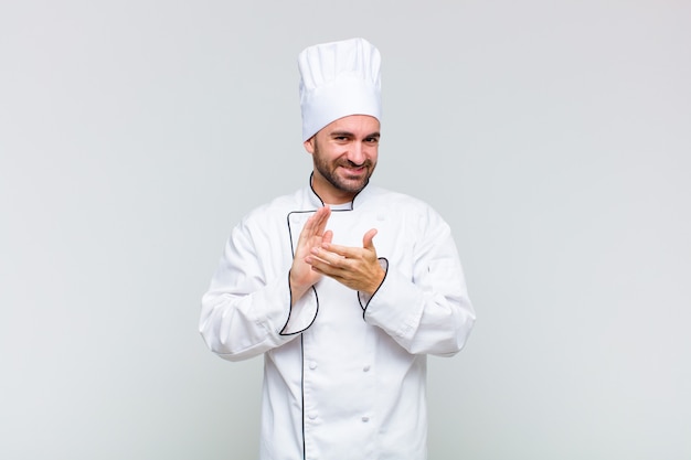 Bald man feeling happy and successful, smiling and clapping hands, saying congratulations with an applause