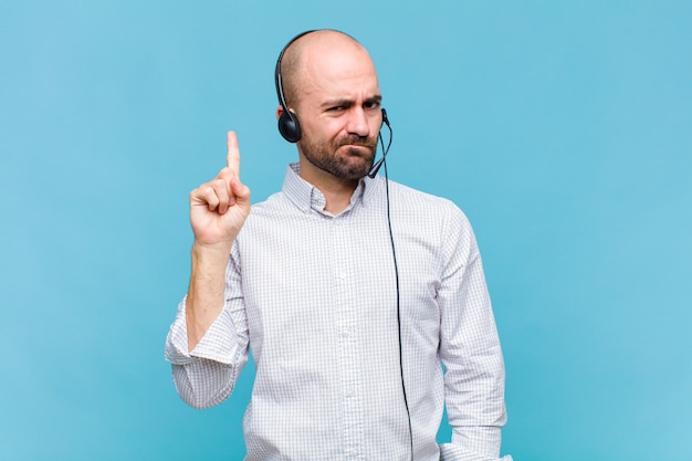 Bald man feeling like a genius holding finger proudly up in the air after realizing a great idea, saying eureka