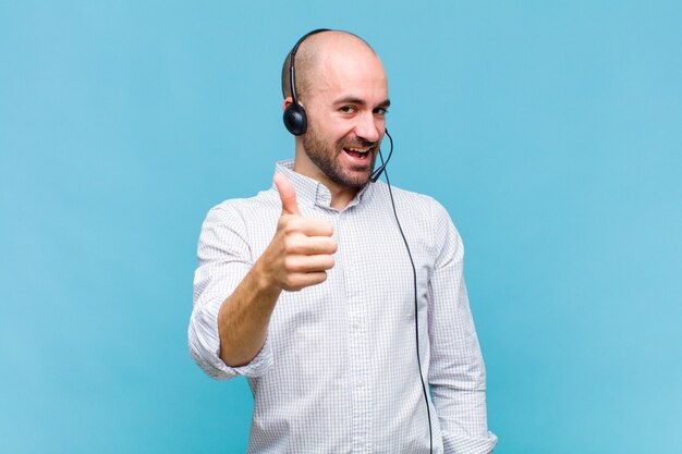 Bald man feeling proud, carefree, confident and happy, smiling positively with thumbs up