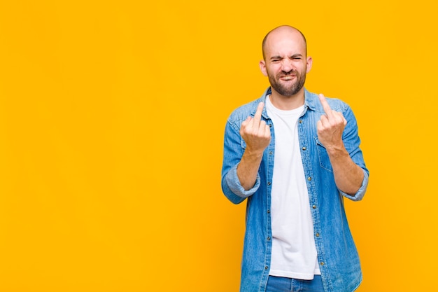 Bald man feeling provocative, aggressive and obscene, flipping the middle finger, with a rebellious attitude