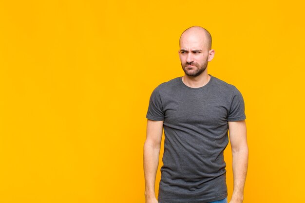 Bald man feeling sad, upset or angry and looking to the side with a negative attitude, frowning in disagreement