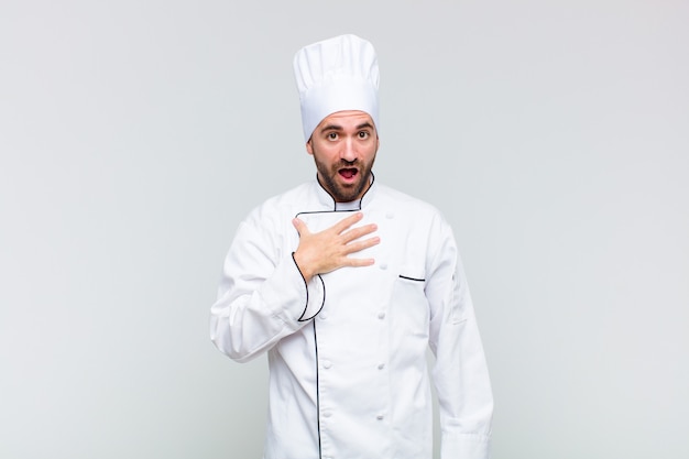 Bald man feeling shocked, astonished and surprised, with hand on chest and open mouth