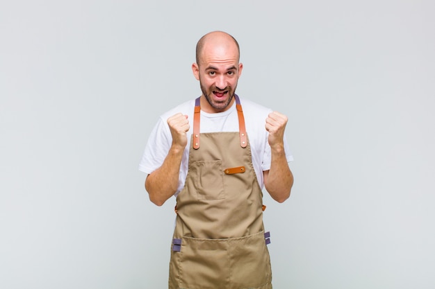 Bald man feeling shocked, excited and happy, laughing and celebrating success, saying wow!