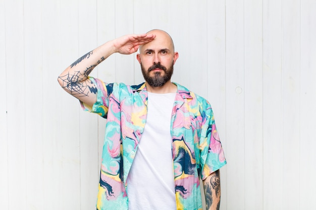 Bald man greeting with a military salute in an act of honor and patriotism, showing respect