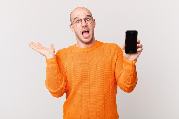 bald man holding a mobile screen