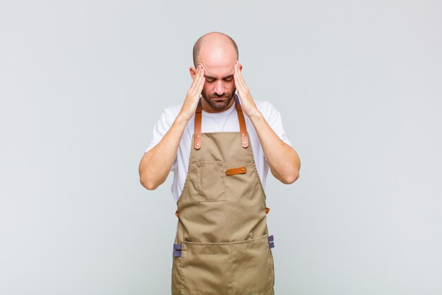 Bald man looking concentrated, thoughtful and inspired, brainstorming and imagining with hands on forehead