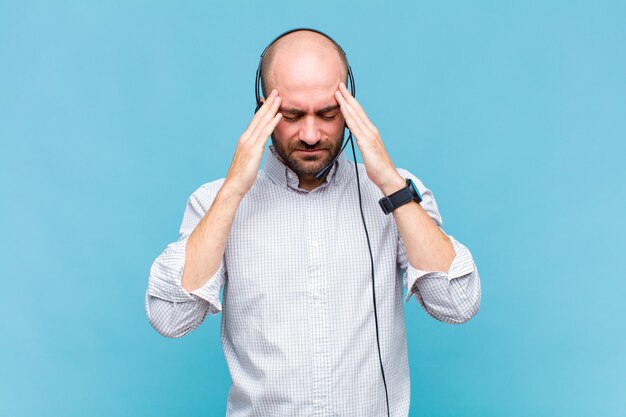 Bald man looking concentrated, thoughtful and inspired, brainstorming and imagining with hands on forehead