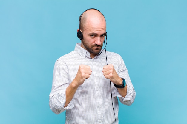 Bald man looking confident, angry, strong and aggressive, with fists ready to fight in boxing position