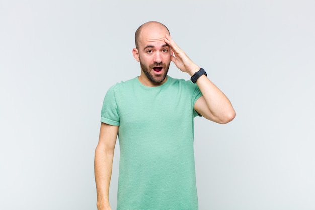 Bald man looking happy, astonished and surprised, smiling and realizing amazing and incredible good news