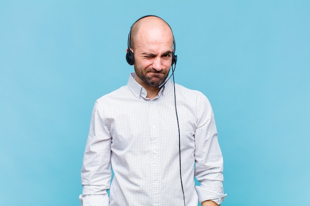 Bald man looking happy and friendly, smiling and winking an eye at you with a positive attitude