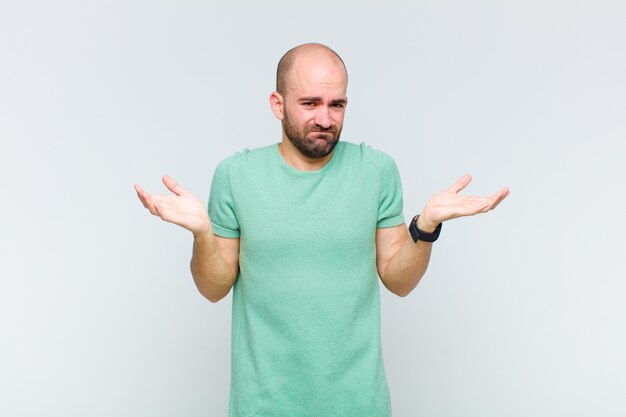 Bald man looking puzzled, confused and stressed, wondering between different options, feeling uncertain