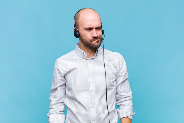 Uomo calvo che sembra perplesso e confuso, chiedendosi o cercando di risolvere un problema o pensando