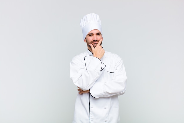 Bald man looking serious, thoughtful and distrustful, with one arm crossed and hand on chin, weighting options