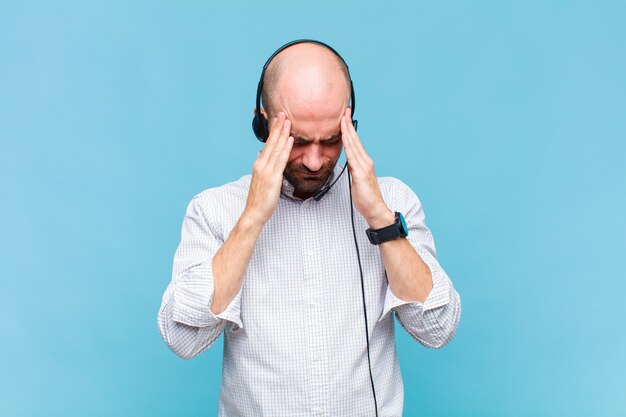 Bald man looking stressed and frustrated, working under pressure with a headache and troubled with problems