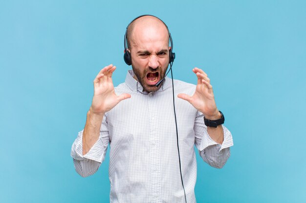 Bald man screaming in panic or anger, shocked, terrified or furious, with hands next to head