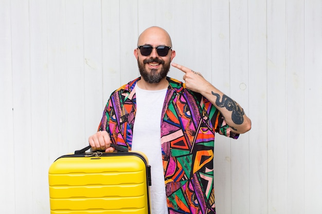 Bald man smiling confidently pointing to own broad smile, positive, relaxed, satisfied attitude