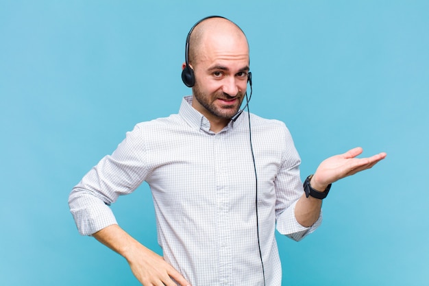 Bald man smiling, feeling confident, successful and happy, showing concept or idea on copy space on the side