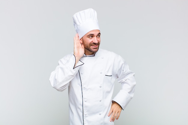 Bald man smiling, looking curiously to the side, trying to listen to gossip or overhearing a secret