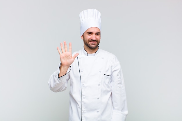 Bald man smiling and looking friendly, showing number five or fifth with hand forward, counting down