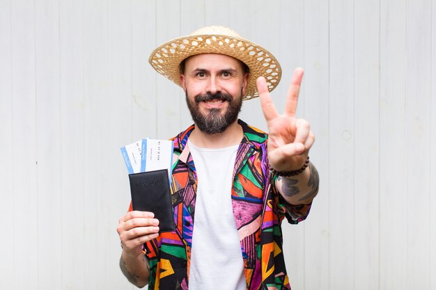 Bald man smiling and looking happy, carefree and positive, gesturing victory or peace with one hand