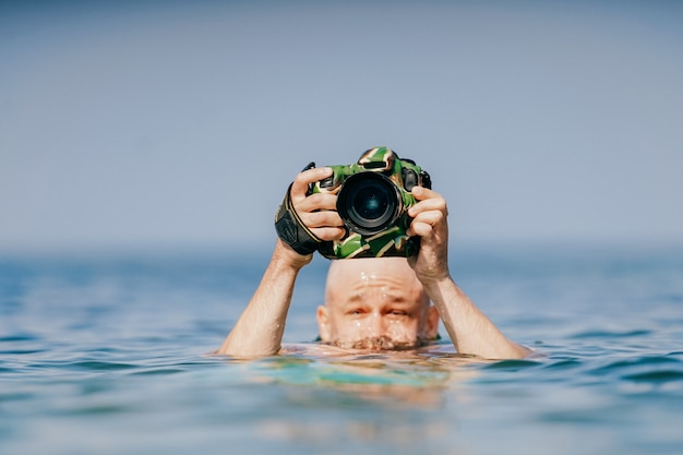 海でカメラを持つハゲ男