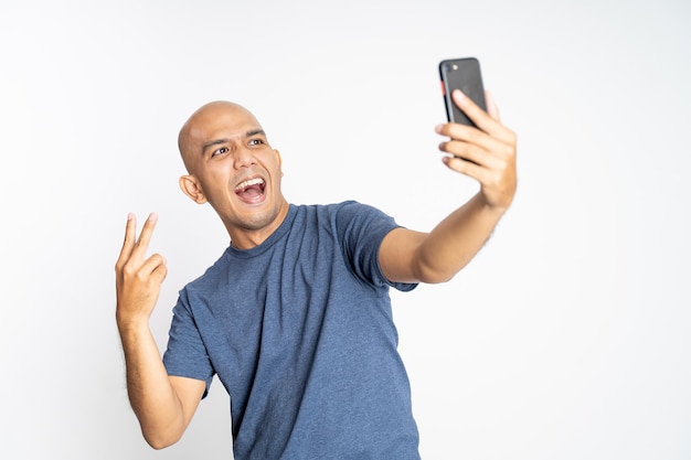 Bald man with peace hand gesture selfie with phone camera