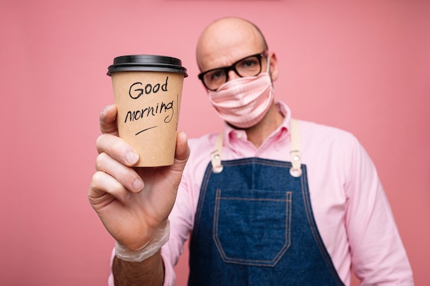 Bald mature man with face mask and coffee in recyclable cardboard cup