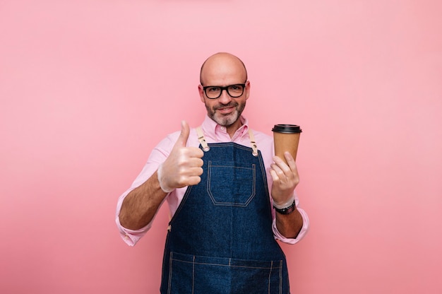 Uomo maturo calvo con il dito sull'espressione e caffè in tazza di cartone riciclabile