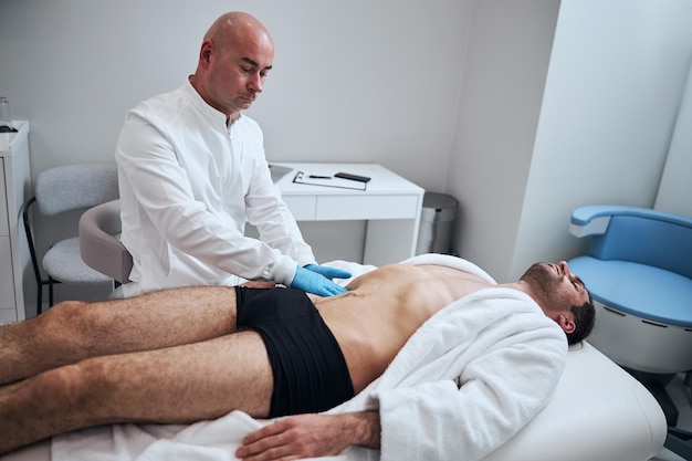 Bald specialist examining male patient in office