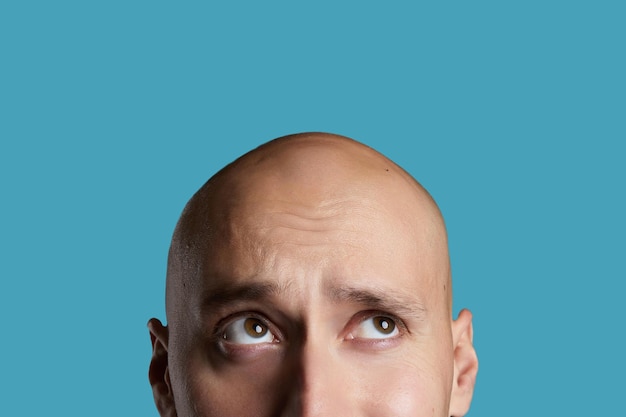 Bald young guy closeup on an empty blue background