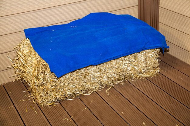 Bale of hay on floor near wooden wall