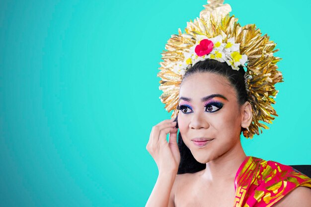 Balinese dancer using a sponge to apply foundation on her face in the studio