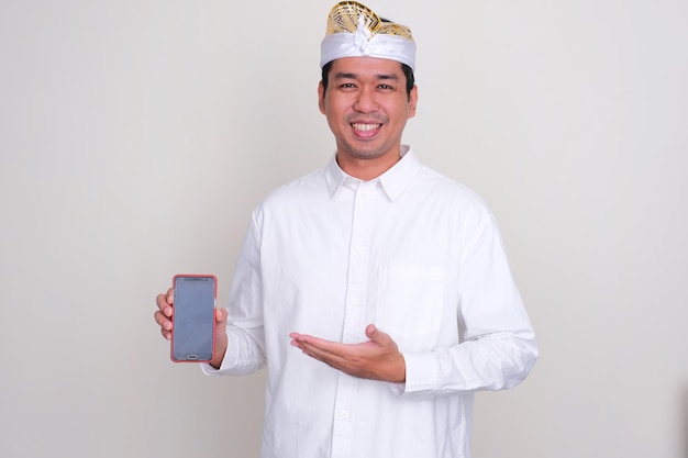Балиец улыбается и указывает на пустой экран мобильного телефона, который он держит
