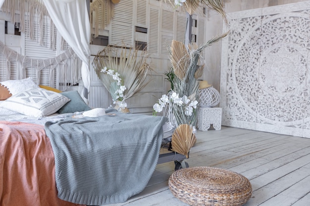 Balinese style bedroom interior. canopy bed with lots of textiles for decoration and wicker items in soft pastel colors