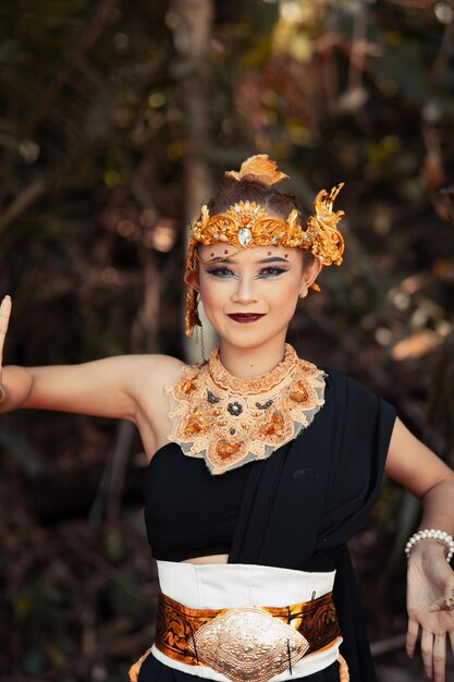 Balinese woman wearing a gold crown and gold necklace in her makeup with a beautiful face