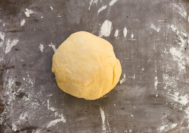 Ball of dough on powdered by flour wooden background