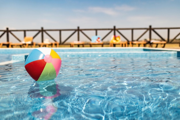 The ball floats on the water surface in the pool under the summer sun