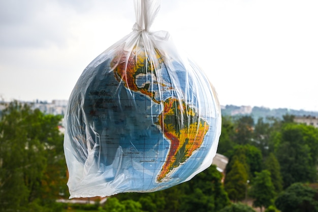 Photo ball in the form of a globe is in a plastic bag as concept of plastic pollution of earth