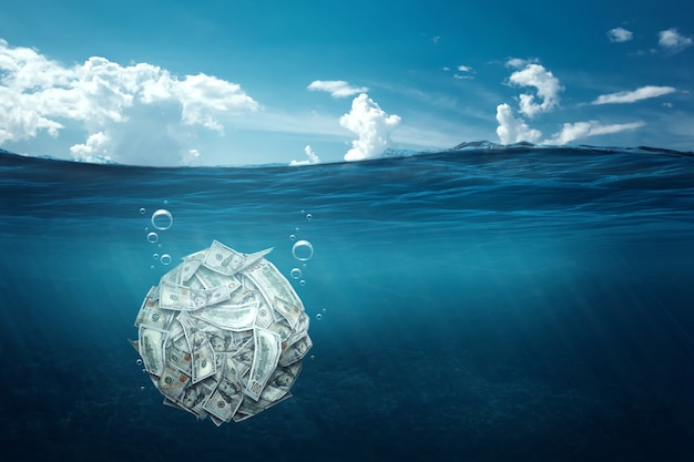 A ball made of dollars sinks under water. Financial crisis concept, debts, paying bills, mortgage, bankruptcy.