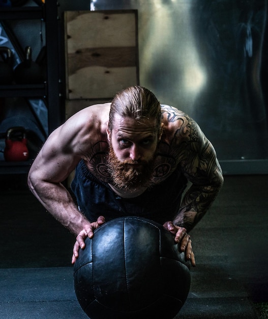 Foto l'uomo della palla alza la barba spinge la medicina atletica spinge il concetto di fitness caucasico muscolare sexy dall'allenamento