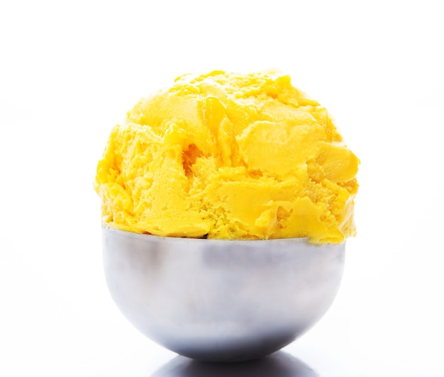 Una pallina di gelato al mango naturale in un cucchiaio.